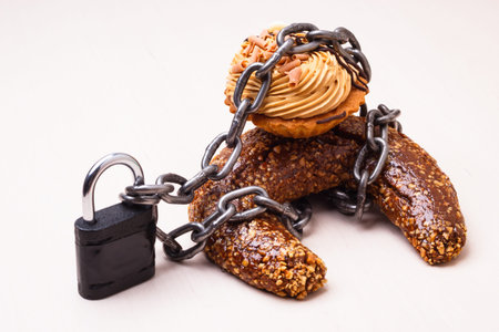 Diet sugar sweet food addiction concept. Cake cupcake wrapped in metal chain and padlock