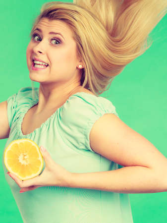 Healthy diet, refreshing food full of vitamins. Woman holding sweet delicious citrus fruit, lemon halfの写真素材