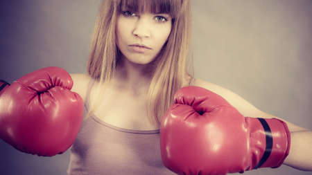 Sporty woman wearing red boxing gloves, fighting. Studio shot on grey, background.の写真素材