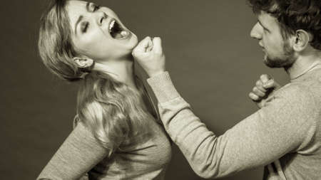Violence against woman. Aggressive man yelling shouting on scared afraid woman. Negative relations in partnership. Expressive young male beating frightened lady.の写真素材