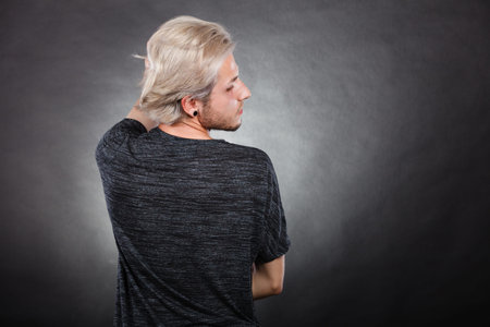 Handsome young fashion model with colored hair highlighted stylish haircut, ear plug, side view