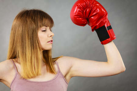 Sporty woman wearing red boxing gloves, fighting. Studio shot on grey, background.の写真素材