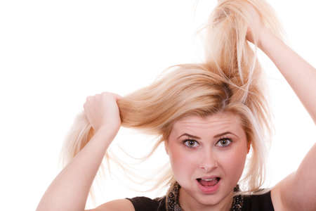 Hair care mistakes, bleaching problems concept. Blonde woman holding her dry, damaged hair.の写真素材