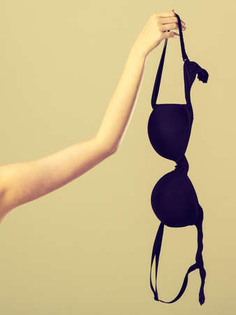 Bosom concept. Female hand holding black plunge braの写真素材