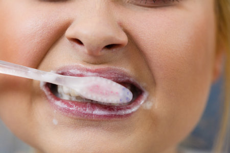 Woman brushing cleaning teeth closeup. Blonde girl with toothbrush in bathroom. Oral hygiene.