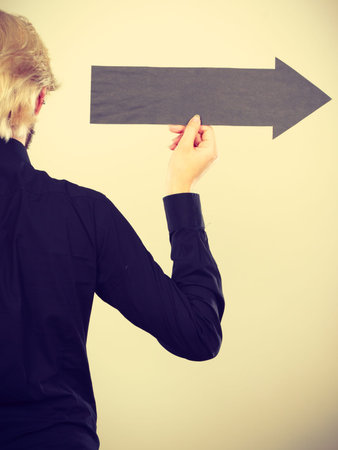 Planning, directions, choices concept. Man holding black arrow pointing right.