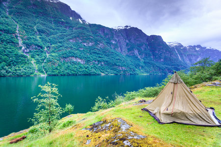 Tourism vacation and travel. Mountains landscape fjord and tent on warer shore, Norway Scandinavia...