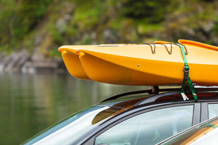 Active lifestyle sport concept. Car with kayak yellow canoe on top roof ready to transportationの写真素材
