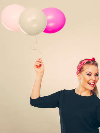 Craziness and lots of fun. Cute crazy joyful girl playing with colored balloons. Blonde playful retro style woman feel craze.の写真素材