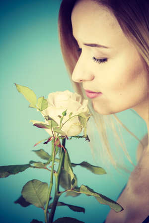 Shot of woman holding romantic rose flower. Women day, valentines gift. Studio shot on blue background.の写真素材