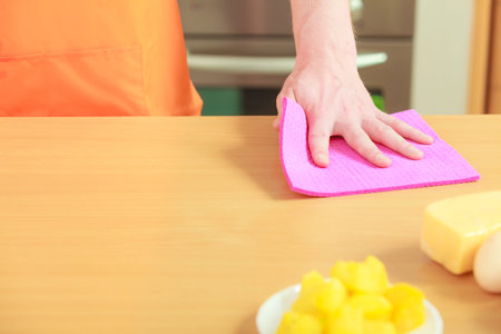 People, housework and housekeeping concept - closeup male hand cleaning table with rag at home...