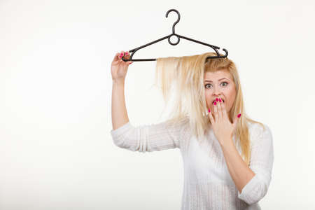 Wardrobe accessories, haircare, hair styling and selling concept. Blonde woman holding hair on clothes hangerの写真素材