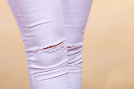 Fashion and current trends concept. Detailed closeup of white woman trousers with holes on kneesの写真素材