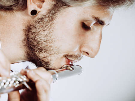Flute music playing professional male flutist musician performer. Young elegant stylish man with instrument, close upの写真素材