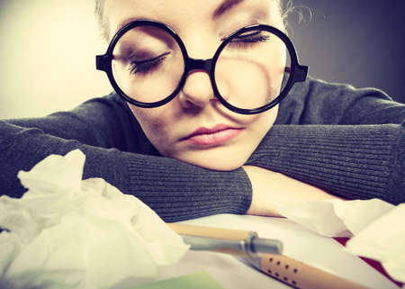 Health concept at business work. Tired overworked young businesswoman secretary manager. Sick ill young female sleeping at workplace.の写真素材