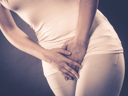 Young sick woman with hands holding pressing her crotch lower abdomen. Medical or gynecological problems, healthcare conceptの写真素材