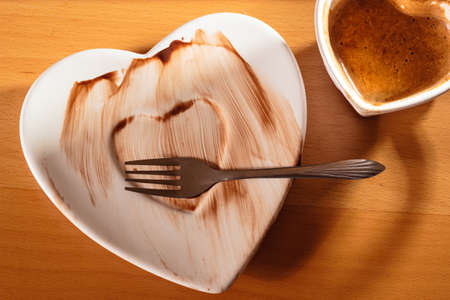 Closeup of heart shaped mug cup of coffee and dirty saucer plate. Top view.の写真素材