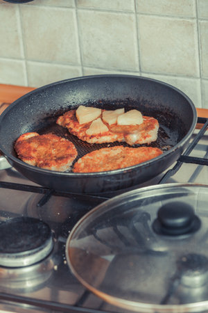 Frying breaded chicken cutlet with pineapples on fry pan. Making dinner meal.の写真素材