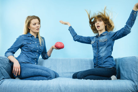 Friendship, human relations concept. Two women friends or sisters wearing jeans shirts, thinking...