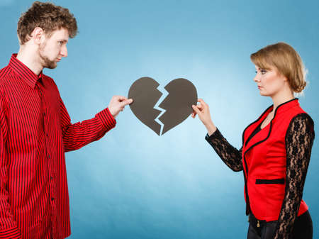 Break up and leave in relationship. Negative emotions between people in love. Young couple with two halves of broken heart. Lovers breaking up.の写真素材