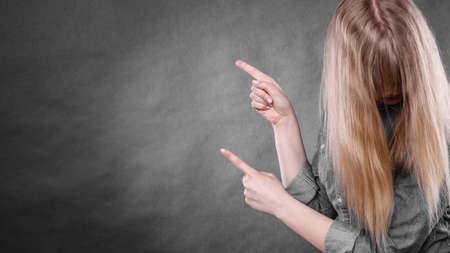 Messages and new information concept. Young blonde casual woman covering her face by hair. Girl showing presenting copy space.の写真素材