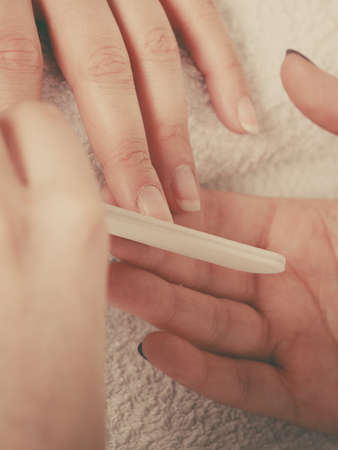 Woman hand on towel, beautician file nails. Beauty wellness spa treatment, manicure conceptの写真素材
