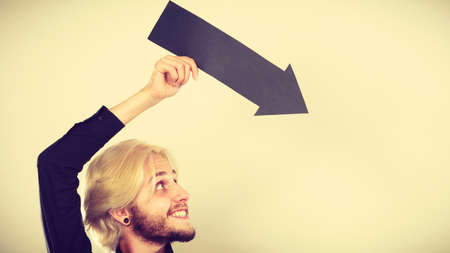 Planning, directions, choices concept. Man holding black arrow pointing right. Indoor shot on light backgroundの写真素材