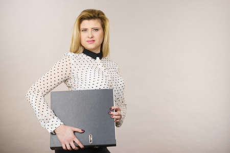 Focused business woman holding binder with documents and paperwork, thinking about problem solution and new ideas.の写真素材