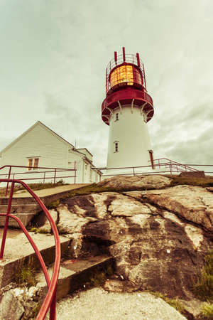 Historic red white lighthouse on the edge of rocky sea coast, South Norway, Lindesnes Fyr beaconの写真素材
