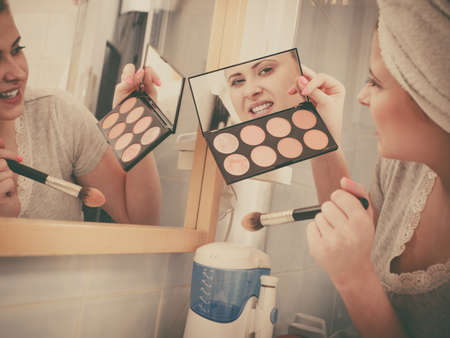 Contouring face kit, visage and make up concept. Woman in bathroom applying contour bronzer on brushの写真素材