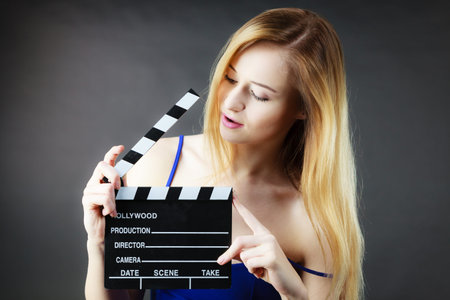 Woman holding professional film slate, movie clapper board. Hollywood production objects concept. Studio shot on black background.の写真素材