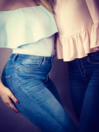 Two unrecognizable women having fashionable outfits, blue jeans and colorful shirts. Fashion and clothing concept.の写真素材