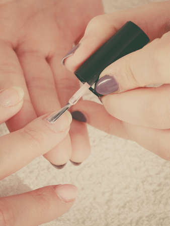 Closeup of beautician painting nails of female client. Woman in beauty spa salon doing manicureの写真素材
