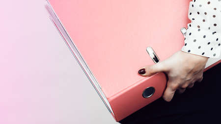 Woman hand holding pink binder with many documents. Office, bookkeeping objects concept.の写真素材