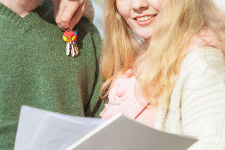 Real estate and family concept. Couple holds blueprint project showing their new house keysの写真素材