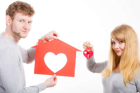 Romance feelings family security future concept. Heart within house. Young couple holding home keys love symbols. Girl and boy presenting.の写真素材