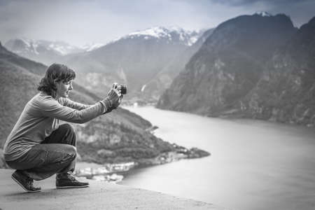 Tourism and travel. Woman tourist taking photo with camera, enjoying mountains fjords view in Sogn og Fjordane county. Norway Scandinavia, black and white photoの写真素材