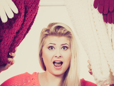 Woman standing in wardrobe with winter clothes, can not decide what to wear. Picking winter clothing concept.の写真素材