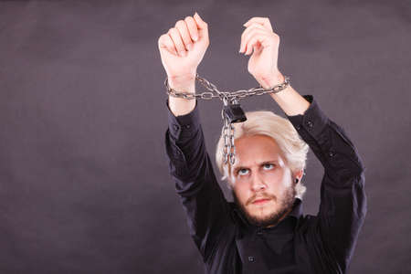 No freedom, social problems concept. Furious man with chained hands, studio shot on dark grunge backgroundの写真素材