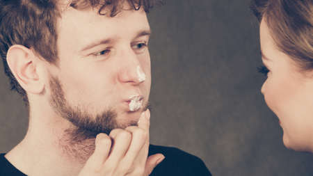 Hygiene and skincare concept. Young blonde female beautician cosmetician apply cream on male mouth lips. Woman and man playing with cosmetic.の写真素材