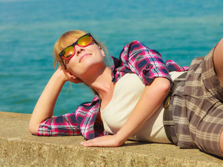 Summer vacation relax and traveling concept. Young tourist woman hiker relaxing on sea shore enjoying sunlightの写真素材