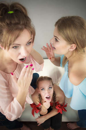 Woman being gossiped bullied by two female friends. Friendship difficulties, rivaly and envy problems.の写真素材