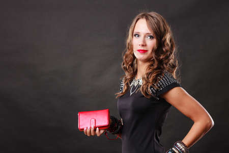 Fashion elegant evening outfit. Close up elegant woman holding red leather handbag clutch bag on dark backgroundの写真素材