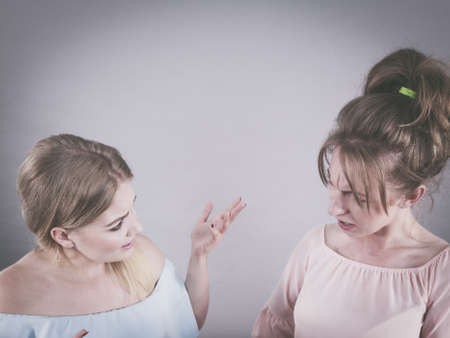 Two young pretty women being mad at each other after argue of fight. Friendship rivaly and envy problems.の写真素材