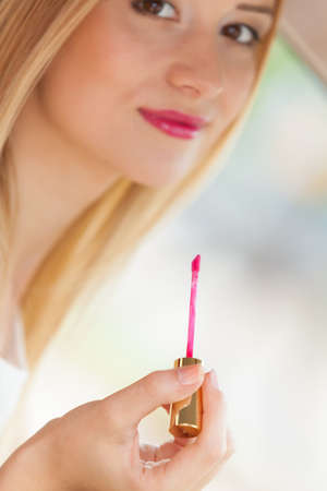 Young attractive woman painting her lips with lipgloss, doing applying make upの写真素材