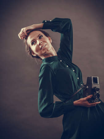 Woman retro style long dark gown taking picture with old camera, vintage photoの写真素材