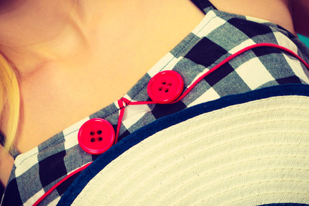 Tailoring, patterns concept. Woman wearing retro checked black and white dress with two red buttons...