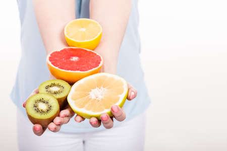 Healthy diet, refreshing food full of vitamins. Woman holding fruits kiwi. orange, lemon and grapefruitの写真素材