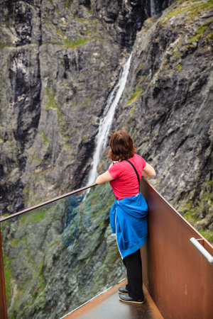 Travel, beauty in nature. Tourist woman looking at mountains waterfall from Trollstigen viewing...