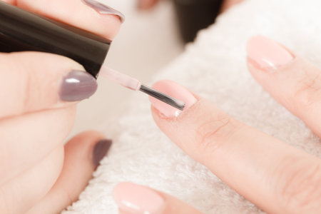 Closeup of beautician painting nails of female client. Woman in beauty spa salon doing manicureの写真素材